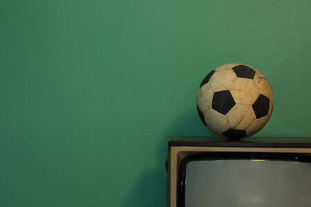 An old soccer ball on a retro TV with retro green paint wallの写真素材