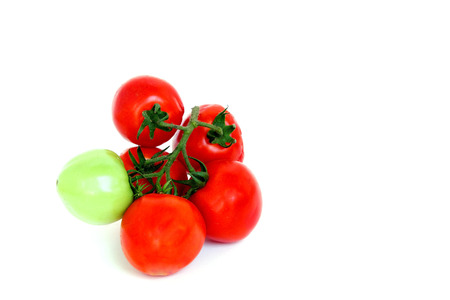 Bunch of red tomatoes with one green on white backgroundの写真素材