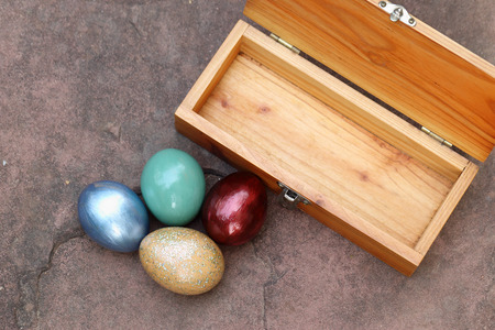 Colorful easter eggs and wooden box on stone floor.の写真素材