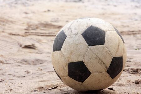 An old football or soccer ball on sand.の写真素材