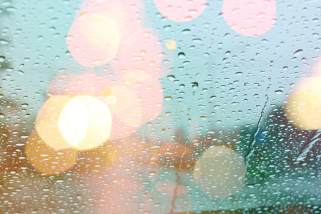 Rain drops on window with light bokeh, rainy season abstract background.の写真素材