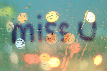 Rain drops and miss you text on window with light bokeh, rainy season abstract background.