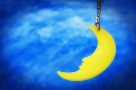 Dreamy moon hanging on string as mobile home decoration with night sky background.の写真素材