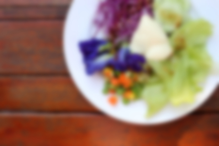 Blurred background of healthy breakfast, fresh vegetable salad on wooden background.の写真素材