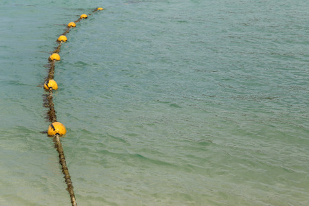 Line of yellow buoys on the rope floating in the sea.の写真素材