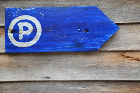 Parking guidepost with letter P, grungy wooden arrow sign isolated on wooden wall.の写真素材