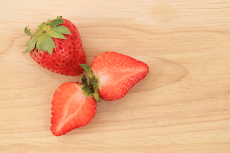 Fresh strawberries full body and halves on wooden background.の写真素材