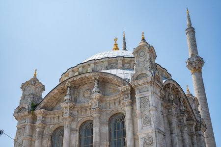 Ortakoy Mosque, showcasing its intricate architecture and detailed stone carving under clear blue sky. Low angle view main dome and elegant minaret of Great Mecidiye Mosqueの写真素材