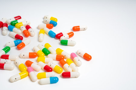 Scattered colorful medicine capsules on isolated white background, vibrant pill assortment. Close up of colorful pills spread out. Health, medication, wellness, treatment conceptの写真素材
