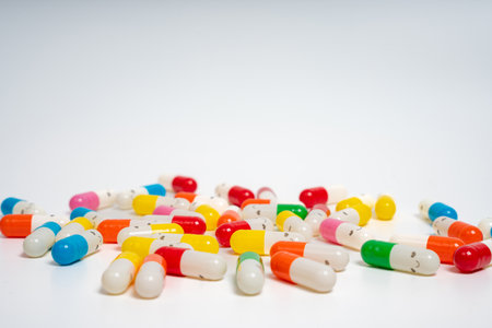 Scattered colorful medicine capsules on isolated white background, vibrant pill assortment. Close up of colorful pills spread out. Health, medication, wellness, treatment conceptの写真素材