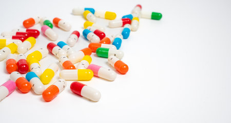 Scattered colorful medicine capsules on isolated white background, vibrant pill assortment. Close up...