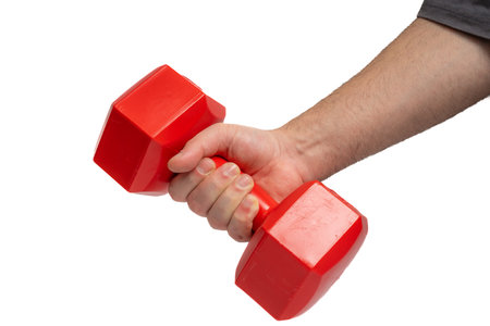 Hand holding red hexagonal dumbbell on isolated white background, fitness gear. Red dumbbell weight held by hand. Strength, health, exercise and training conceptの写真素材
