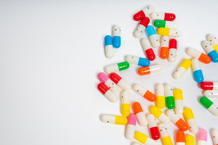 Scattered colorful medicine capsules on isolated white background, vibrant pill assortment. Close-up of colorful pills spread out. Health, medication, wellness, treatment conceptの写真素材