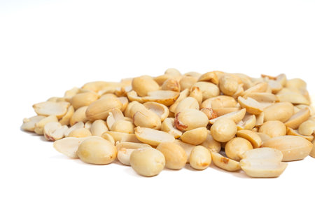 Close-up pile of roasted peeled and halved peanuts isolated on white background. Mound of shelled...