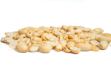 Close-up pile of roasted peeled and halved peanuts isolated on white background. Mound of shelled...