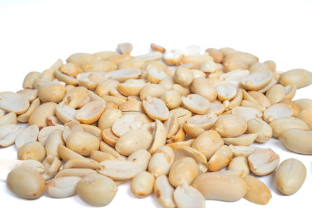 Close-up pile of roasted peeled and halved peanuts isolated on white background. Mound of shelled...