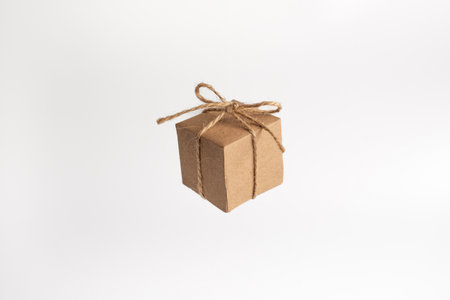 Box package wrapped in brown kraft paper and tied with rough twine, isolated on white background. Floating kraft cube boxの写真素材