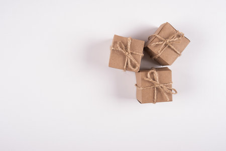 Brown gift boxes wrapped with kraft paper on white background. Top view of gift boxes tied with...