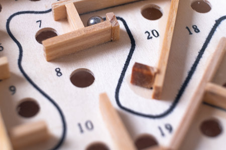 Wooden labyrinth toy marble maze game. Ball bearing navigating a vintage traditional wooden maze, close upの写真素材