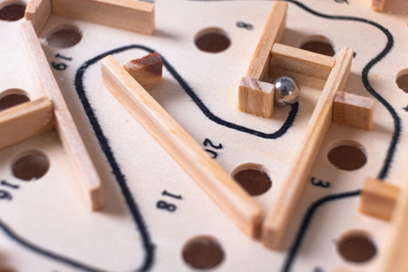 Wooden labyrinth toy marble maze game. Ball bearing navigating a vintage traditional wooden maze, close upの写真素材
