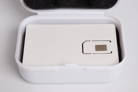 Close-up of a new mobile phone SIM card in its white carrier packaging over an open storage box