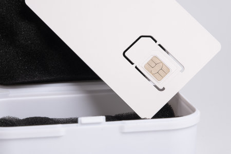 Close-up of a new mobile phone SIM card in its white carrier packaging over an open storage boxの写真素材