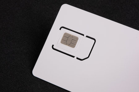 White SIM card isolated on black background. SIM card for mobile phone, close up, top view