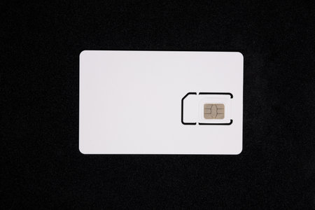 White SIM card isolated on black background. Plastic SIM card for mobile phone, close upの写真素材