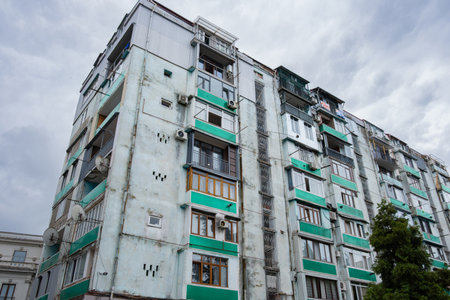 Tall, old apartment building in Batumi, Georgia with many balconies and windows on cloudy day. Exterior view of multi-story buildingの写真素材