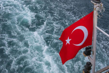 Turkish flag waving on a ship at sea. Red Turkish flag with a white star and crescent, fluttering against a blue sea background. National symbol of Turkeyの写真素材