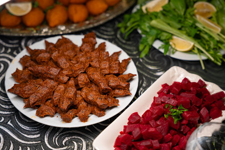 Plate of traditional cig kofte served with beet salad, greens and lemon slices. Traditional middle eastern and turkish cuisine kibbeh. Spicy bulgur raw meatballs. Table dinnerの写真素材