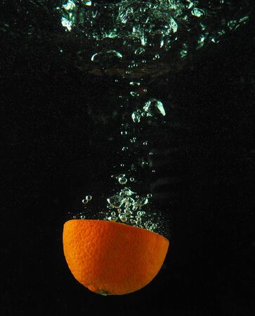 Orange in water with bubbles on a dark backgroundの写真素材