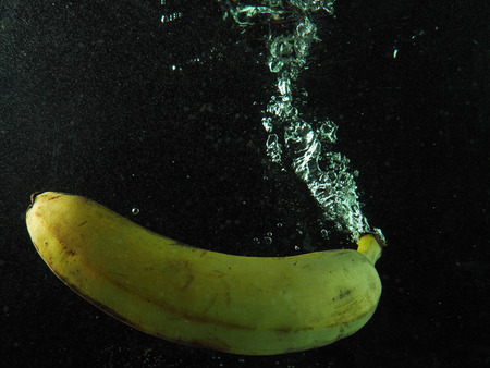 Banana in water with bubbles on a dark backgroundの写真素材