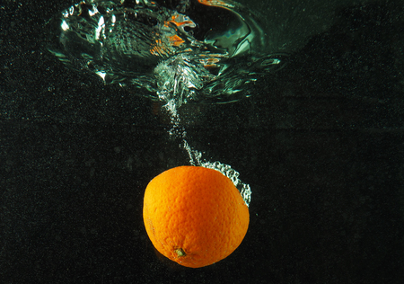 Orange in water with bubbles on a dark backgroundの写真素材
