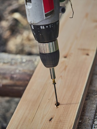 The builder screws the screw into the boardの写真素材