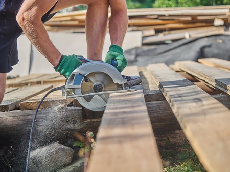The builder cuts the board with a circular sawの写真素材
