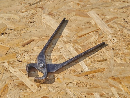 Construction tongs on a wooden background