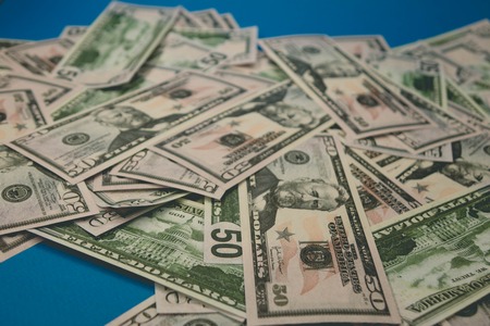scattered dollar bills close-up. fifty dollars blue background.