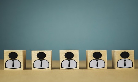 wooden cubes standing in a row, meaning wage workers standing in one line, abstraction on a blue...