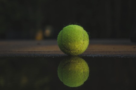 the tennis ball is near the puddle, the ball is reflected in the water.の写真素材