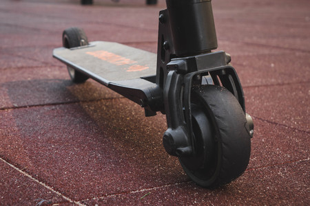black electric scooter standing on the rubber pad in the park, rear in frontの写真素材