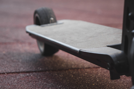 black electric scooter standing on the rubber pad in the park, rear in frontの写真素材
