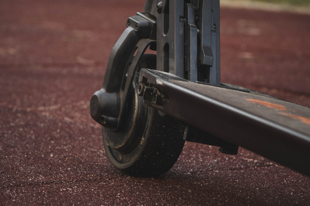 black electric scooter standing on the rubber pad in the park, rear in frontの写真素材