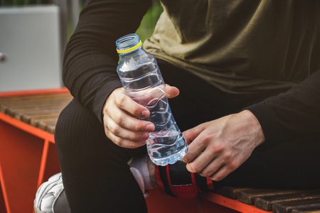 young man in sportsweaat gym holding bottle of water on the sports field.の写真素材