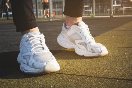male legs shod in white sneakers on the playgroundの写真素材