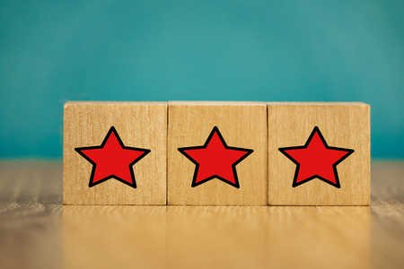 Red stars on wooden cubes on a blue background. Stars mean assessing quality. five-point rating systemの写真素材