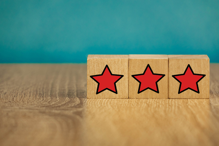 Red stars on wooden cubes on a blue background. Stars mean assessing quality. five-point rating systemの写真素材