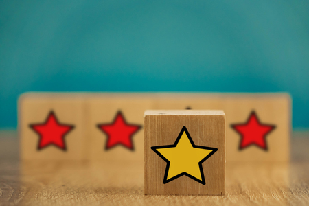star icon yellow and red on wooden cubes far from blue background.の写真素材