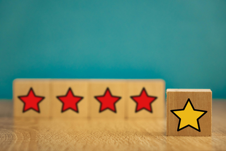 star icon yellow and red on wooden cubes far from blue background.の写真素材