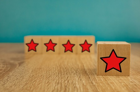 Red stars on wooden cubes on a blue background. Stars mean assessing quality. five-point rating...